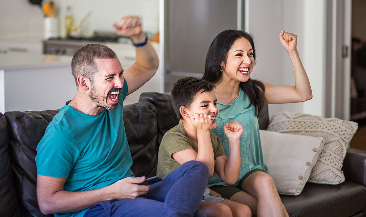 Family of three cheering at TV